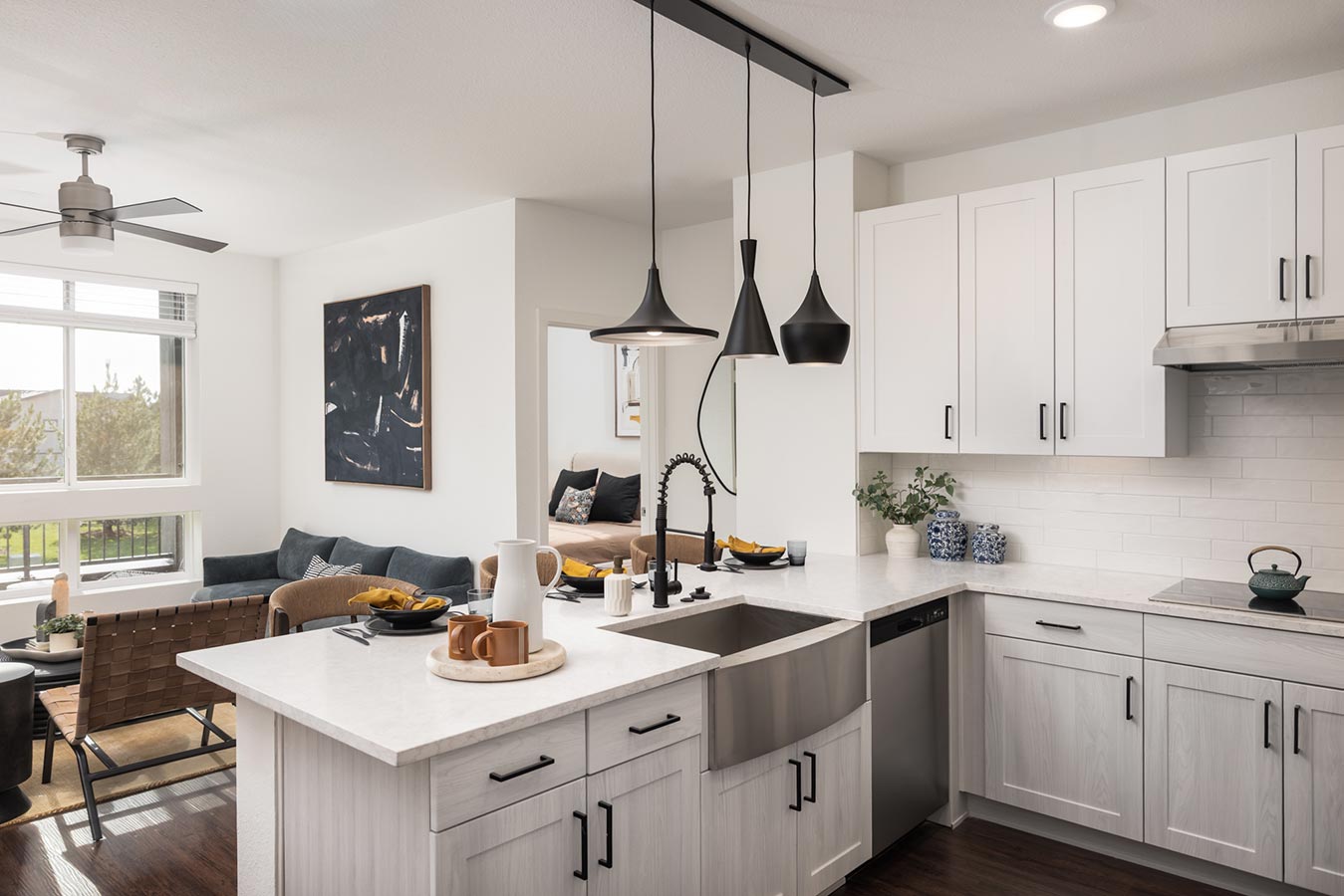 View from kitchen with white cabinets and floor to ceiling windows in living room