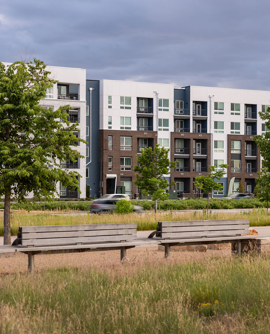Street view of exterior buildings and benches at RYE Central Park apartments near the light rail in Denver.